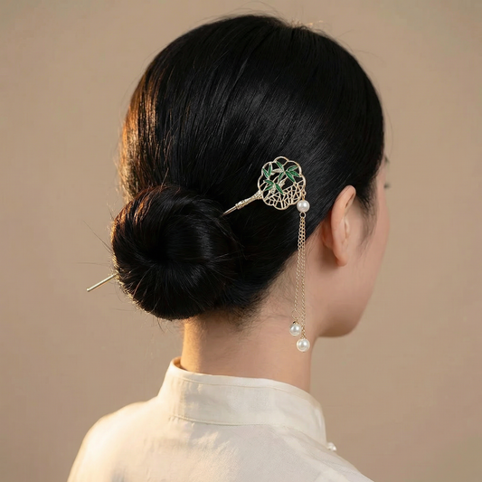 Bamboo medallion hair stick worn in a low bun rear view showing openwork medallion and dangling pearl chain tassels — Hanarai