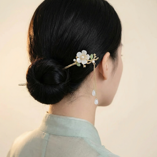 Gold flower hair stick worn in elegant low bun showing chain teardrop drops