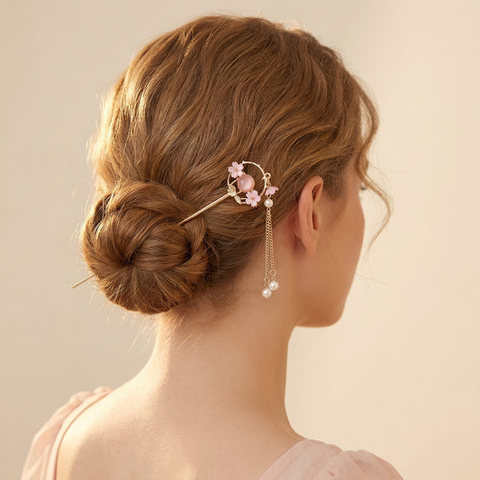 Cherry blossom hair stick worn in elegant low bun with pearl chain drop draping