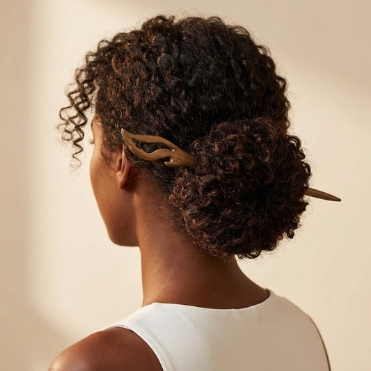 Carved wood hair stick worn in curly low bun showing openwork flame detail