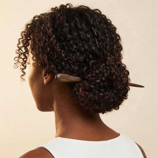 Dark wood hair stick worn in curly low bun showing smooth rounded tip