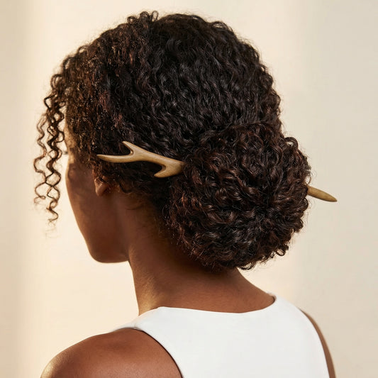 Forked branch wood hair stick worn in curly low bun showing triple-prong tip